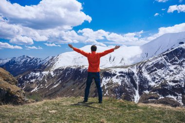 Dağın tepesindeki adam. Kavramsal sahne. Sırt çantalı genç adam dağın tepesinde duruyor ve vadi manzarasının keyfini çıkarıyor.