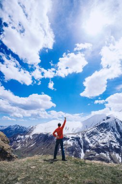 Dağın tepesindeki adam. Kavramsal sahne. Sırt çantalı genç adam dağın tepesinde duruyor ve vadi manzarasının keyfini çıkarıyor.
