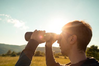 Genç adam ormanda dürbünü kullanıyor. Turist Kampı