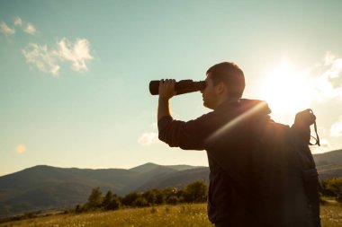 Genç adam ormanda dürbünü kullanıyor. Turist Kampı