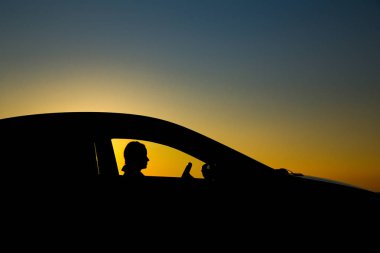 Sedan arabanın silueti ve arka planda güzel bir günbatımı kızı.