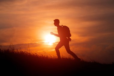 Turist silueti bir dağın tepesine uzanmış günbatımının tadını çıkarıyordu. Spor ve aktif yaşam konsepti