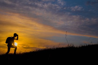 Hayallerinin peşinden git, gün batımında insan silueti. Sırt çantalı bir yürüyüşçü sahada yürüyor. Gün batımında Yaz sağlıklı aktif yaşam tarzı. Tek yolculuk..