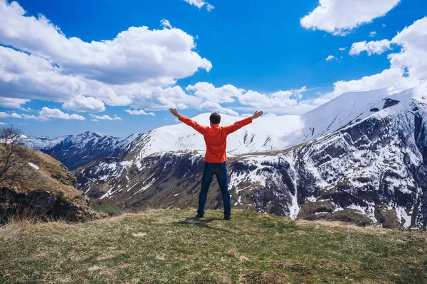 Dağın tepesindeki adam. Kavramsal sahne. Sırt çantalı genç adam dağın tepesinde duruyor ve vadi manzarasının keyfini çıkarıyor.