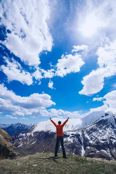Dağın tepesindeki adam. Kavramsal sahne. Sırt çantalı genç adam dağın tepesinde duruyor ve vadi manzarasının keyfini çıkarıyor.