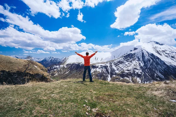 Dağın tepesindeki adam. Kavramsal sahne. Sırt çantalı genç adam dağın tepesinde duruyor ve vadi manzarasının keyfini çıkarıyor.