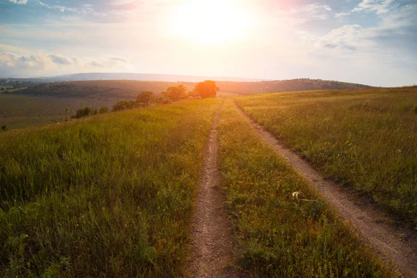 red sunset over green field with road.Road lane and deep sky. Nature design.