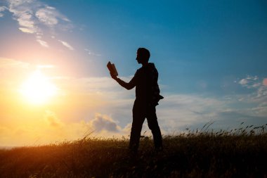 Parkta kitap okuyan adam. Akşamları denizin kenarında dalgakıran üzerinde oturan bir adamın silueti, kitap okuyor.