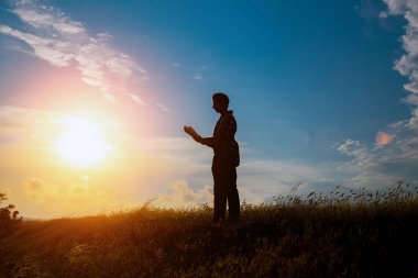 Parkta kitap okuyan adam. Akşamları denizin kenarında dalgakıran üzerinde oturan bir adamın silueti, kitap okuyor.