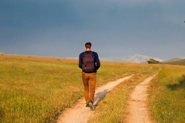 Genç adam bir kırsal yolda yürürken.