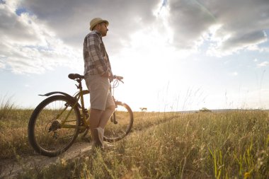 Spor dünyasının silueti güzel günbatımında sahada bisiklet sürüyor.