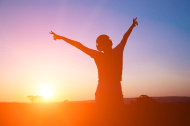 Kulaklık gündoğumu zemin üzerine siluet genç kadınla.