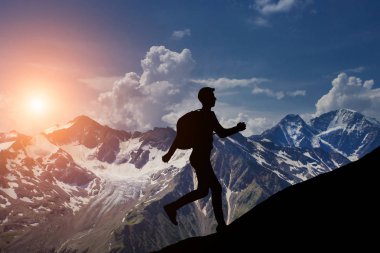 İnsan güzel bir gün batımına karşı bir tepede koşar.