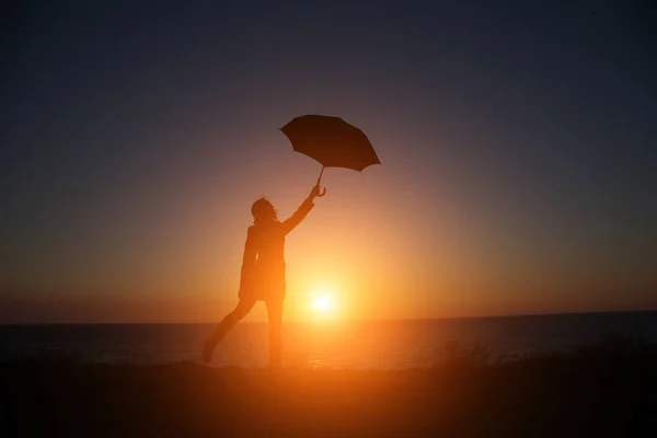 海を望む傘を手に美しい夕日を背景に人々 — ストック写真