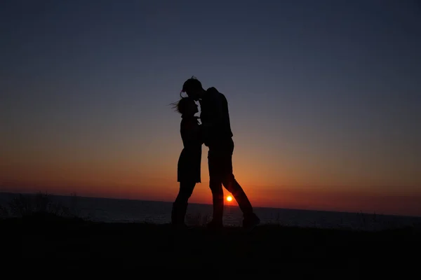 在美丽的夕阳西下手牵手勾勒轮廓的男人和女孩 — 图库照片
