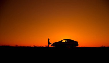 Genç kızla ve kırık araba. Sedan araba güzel gün batımı arka plan üzerinde kızla silüeti