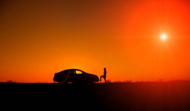 Genç kızla ve kırık araba. Sedan araba güzel gün batımı arka plan üzerinde kızla silüeti