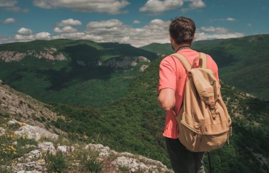 Bir dağın tepesinde kaldırdı elleriyle ayakta ve vadi manzaralı zevk sırt çantası ile genç adam