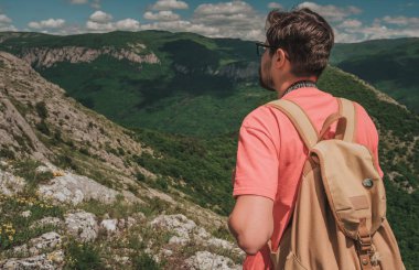 Bir dağın tepesinde kaldırdı elleriyle ayakta ve vadi manzaralı zevk sırt çantası ile genç adam