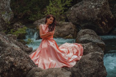 Uçan kumaş, sallayarak ile muhteşem pembe elbiseli Genç kadın moda Nehri yakınında park kadın poz