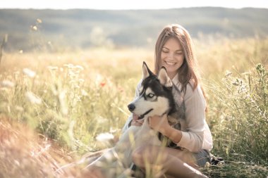 Komik husky köpek ile açık havada parkında oynayan güzel ve genç birbayan. Yaz ve günbatımı
