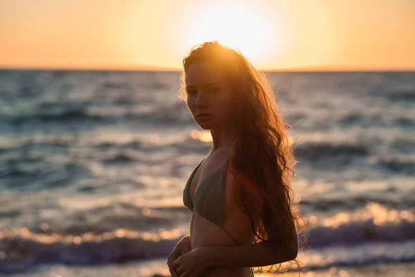 young slim beautiful woman on sunset beach, playful, dancing, running, bohemian outfit, indie style, summer vacation, sunny, having fun, positive mood, romantic, splashing water, silhouette, happy, photo toned