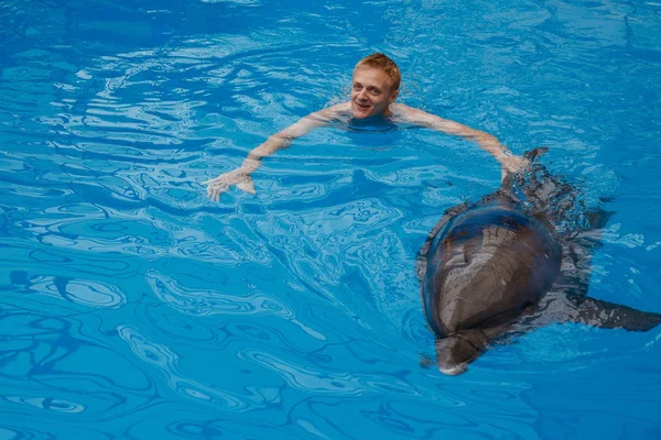 happy man swim with dolphin in dolphinarium