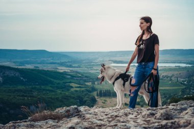 Gün batımında dağlarda bir köpek (gri ve beyaz husky) ile güzel kız çalış