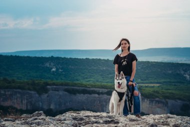 Gün batımında dağlarda bir köpek (gri ve beyaz husky) ile güzel kız çalış