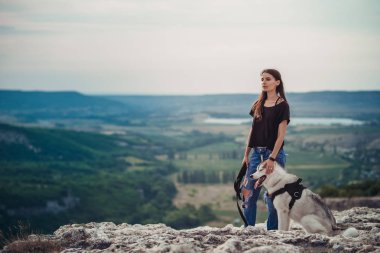 Gün batımında dağlarda bir köpek (gri ve beyaz husky) ile güzel kız çalış