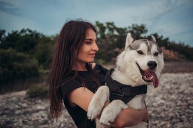 Gün batımında dağlarda bir köpek (gri ve beyaz husky) ile güzel kız çalış