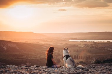 Gün batımında dağlarda bir köpek (gri ve beyaz husky) ile güzel kız çalış