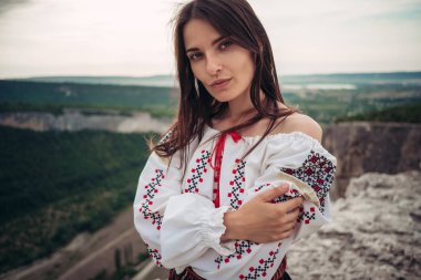 Atractive kadın geleneksel Romen kostüm dağda yeşil arka plan bulanık. Açık fotoğraf. Gelenekler ve kültürel çeşitlilik