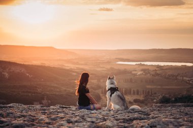 Gün batımında dağlarda bir köpek (gri ve beyaz husky) ile güzel kız çalış