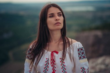Atractive kadın geleneksel Romen kostüm dağda yeşil arka plan bulanık. Açık fotoğraf. Gelenekler ve kültürel çeşitlilik