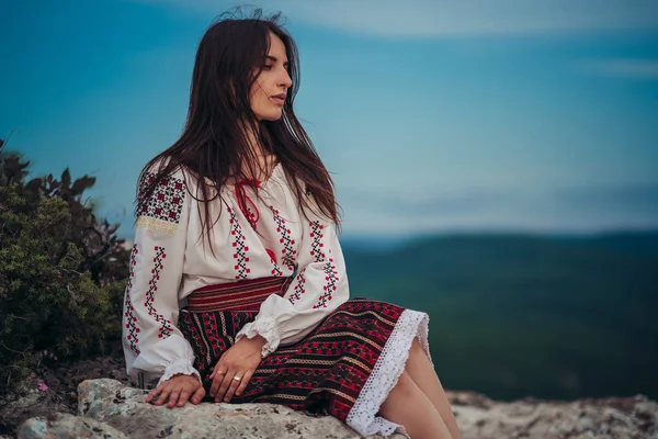 Atractive kadın geleneksel Romen kostüm dağda yeşil arka plan bulanık. Açık fotoğraf. Gelenekler ve kültürel çeşitlilik