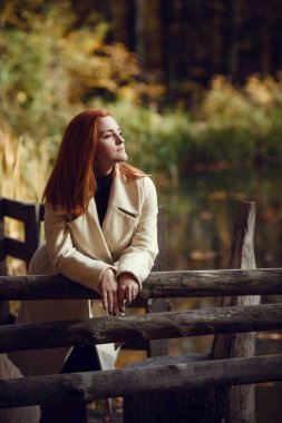 Beyaz önlük sonbaharda kırmızı saçlı güzel, romantik ve hüzünlü kız portresi.