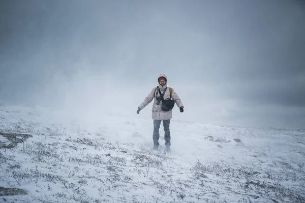 Wintery scene of shivering man in snowstorm or ice storm. Man walking in the snowstorm in the mountains