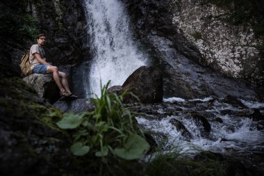 Genç yalınayak turist giyen kot pantolon kısa ve sittin sırt çantası