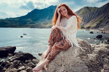 Güneş ışığı altında sahilde poz beyaz tığ işi mayo giyen güzel boho tarz modeli