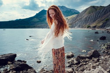 Güneş ışığı altında sahilde poz beyaz tığ işi mayo giyen güzel boho tarz modeli