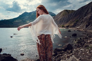 Güneş ışığı altında sahilde poz beyaz tığ işi mayo giyen güzel boho tarz modeli