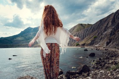 Güneş ışığı altında sahilde poz beyaz tığ işi mayo giyen güzel boho tarz modeli