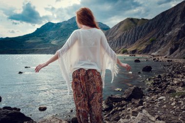 Güneş ışığı altında sahilde poz beyaz tığ işi mayo giyen güzel boho tarz modeli