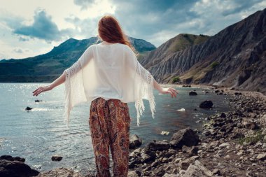 Güneş ışığı altında sahilde poz beyaz tığ işi mayo giyen güzel boho tarz modeli