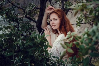 Güneş ışığı altında sahilde poz beyaz tığ işi mayo giyen güzel boho tarz modeli