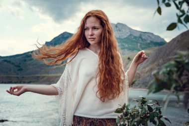 Güneş ışığı altında sahilde poz beyaz tığ işi mayo giyen güzel boho tarz modeli