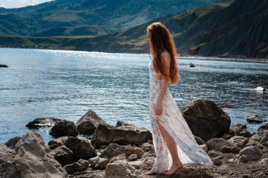 Güzel boho tarz modeli Güneş ışığı altında sahilde poz beyaz elbise