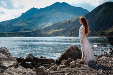 Güzel boho tarz modeli Güneş ışığı altında sahilde poz beyaz elbise