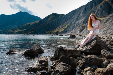 Güzel boho tarz modeli Güneş ışığı altında sahilde poz beyaz elbise